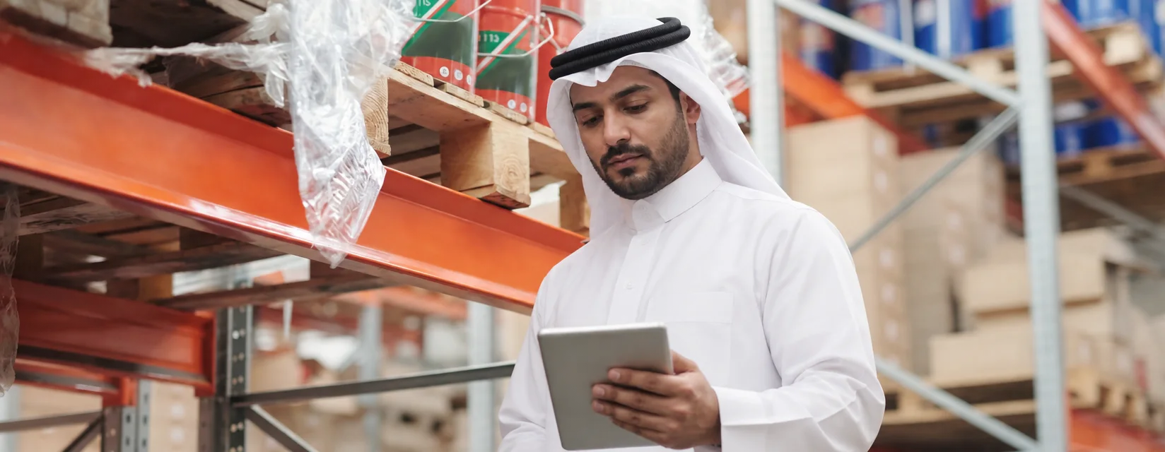 A Saudi employee with a tablet in a warehouse